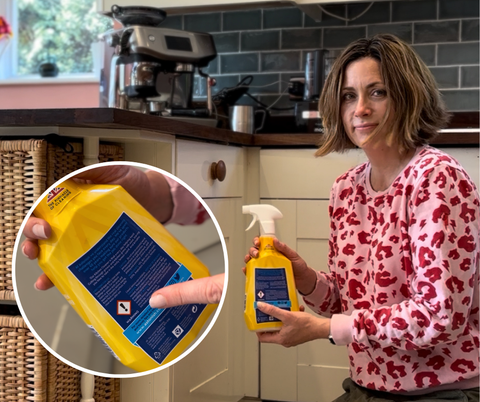 lady holding a householde cleaner with a harsh chemical warning sign